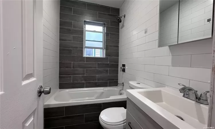 Full bathroom featuring tiled shower / bath, decorative backsplash, vanity, and toilet