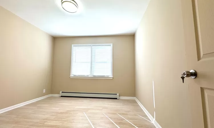 Unfurnished room featuring light hardwood / wood-style flooring and baseboard heating