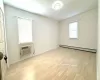 Spare room featuring light wood-type flooring, an AC wall unit, a wealth of natural light, and a baseboard heating unit