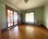 Empty room with dark hardwood / wood-style flooring, ornamental molding, radiator, and french doors