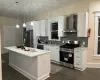 Kitchen with pendant lighting, a center island, wall chimney range hood, sink, and stainless steel appliances