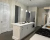 Kitchen with black microwave, a kitchen island, stainless steel fridge, pendant lighting, and white cabinets