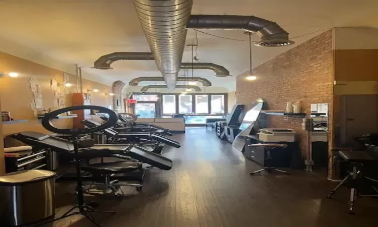 Workout area with wood-type flooring and brick wall