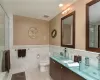 Bathroom featuring tile patterned flooring, vanity, toilet, and tile walls