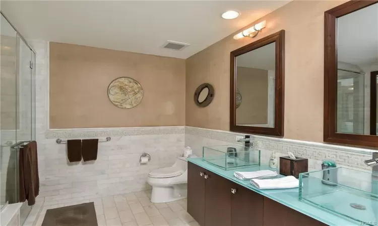 Bathroom featuring tile patterned flooring, vanity, toilet, and tile walls