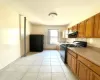 Kitchen with backsplash, sink, light tile patterned floors, and black appliances