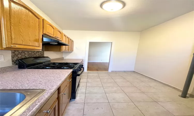 Kitchen featuring sink, light tile patterned floors, and black gas range oven