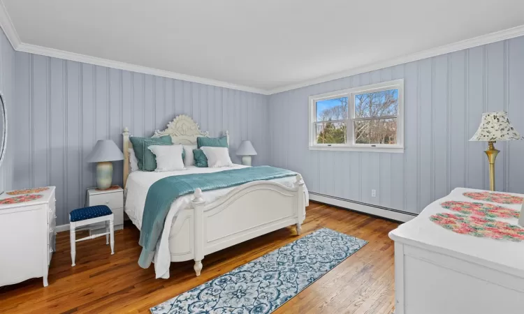 Bedroom with hardwood / wood-style flooring, crown molding, and a baseboard heating unit