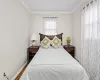 Bedroom with wood-type flooring, crown molding, and a baseboard heating unit