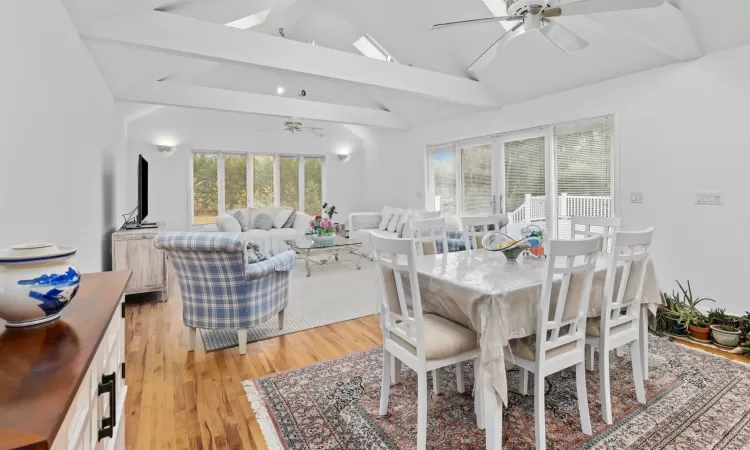 Dining area with beam ceiling, ceiling fan, high vaulted ceiling, and light hardwood / wood-style floors