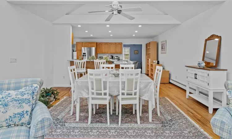 Dining area with ceiling fan, vaulted ceiling, and light hardwood / wood-style flooring