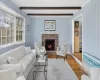 Living room with hardwood / wood-style flooring, beam ceiling, and a brick fireplace