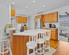 Kitchen featuring a kitchen breakfast bar, kitchen peninsula, range hood, light hardwood / wood-style floors, and stainless steel fridge with ice dispenser