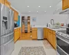 Kitchen with exhaust hood, sink, light tile patterned floors, kitchen peninsula, and stainless steel appliances