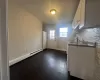 Kitchen with dark wood-type flooring, white cabinets, tasteful backsplash, white fridge, and a baseboard radiator