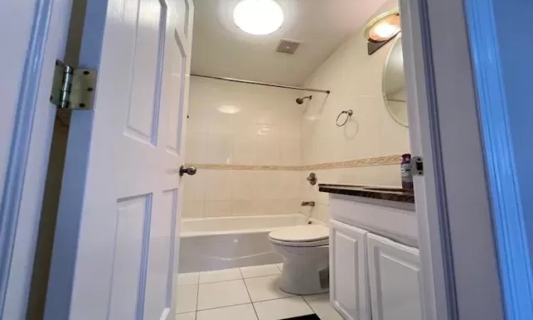 Full bathroom with tile patterned flooring, vanity, tiled shower / bath combo, and toilet