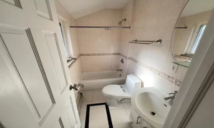 Full bathroom featuring sink, tile patterned floors, shower / bath combination, vaulted ceiling, and tile walls