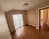 Empty room featuring vaulted ceiling, dark hardwood / wood-style floors, and a wall mounted air conditioner