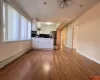 Kitchen with stainless steel refrigerator, white cabinetry, a baseboard radiator, light hardwood / wood-style flooring, and vaulted ceiling