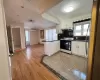 Kitchen with kitchen peninsula, white stove, a wall mounted air conditioner, and white cabinetry