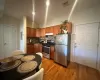 Kitchen featuring decorative backsplash, electric panel, wood-type flooring, and appliances with stainless steel finishes