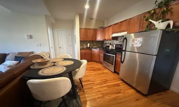 Kitchen with backsplash, light hardwood / wood-style flooring, and appliances with stainless steel finishes