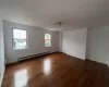 Empty room with dark hardwood / wood-style flooring and a baseboard radiator