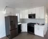 Kitchen featuring tasteful backsplash, sink, black appliances, dark hardwood / wood-style floors, and white cabinetry