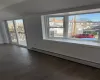 Empty room featuring dark hardwood / wood-style floors, baseboard heating, and a wealth of natural light