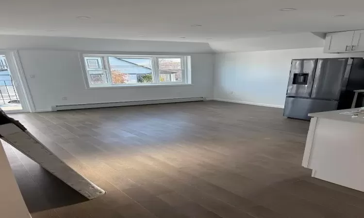 Unfurnished living room featuring dark hardwood / wood-style flooring and a baseboard radiator