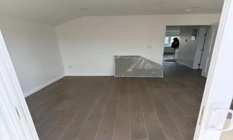 Spare room with lofted ceiling and dark hardwood / wood-style floors