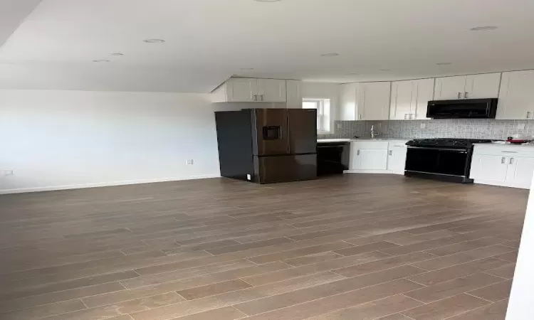 Kitchen featuring dark hardwood / wood-style flooring, white cabinetry, sink, and black appliances