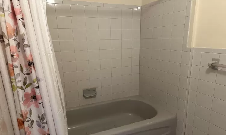 Bathroom with shower / bath combo and tile walls