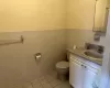 Bathroom with toilet, vanity, tile patterned floors, and tile walls