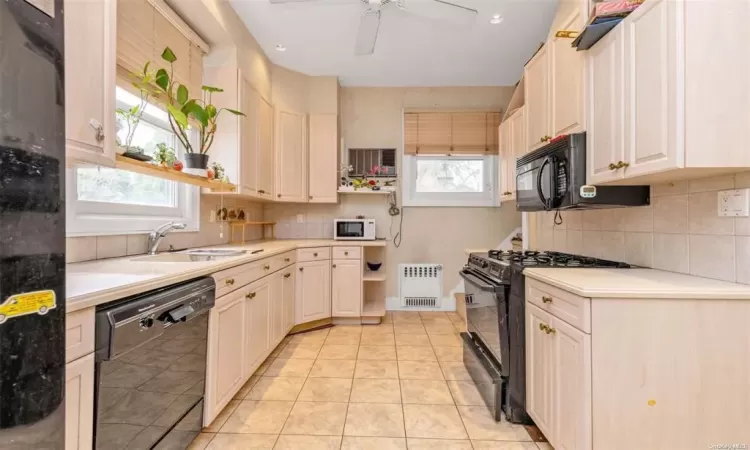 Kitchen featuring black appliances, light tile patterned flooring, a healthy amount of sunlight, and sink