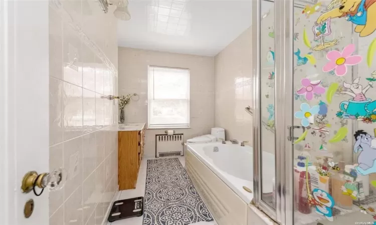 Full bathroom featuring vanity, plus walk in shower, tile patterned floors, toilet, and radiator heating unit