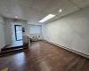 Empty room featuring a paneled ceiling, dark hardwood / wood-style flooring, and a baseboard heating unit