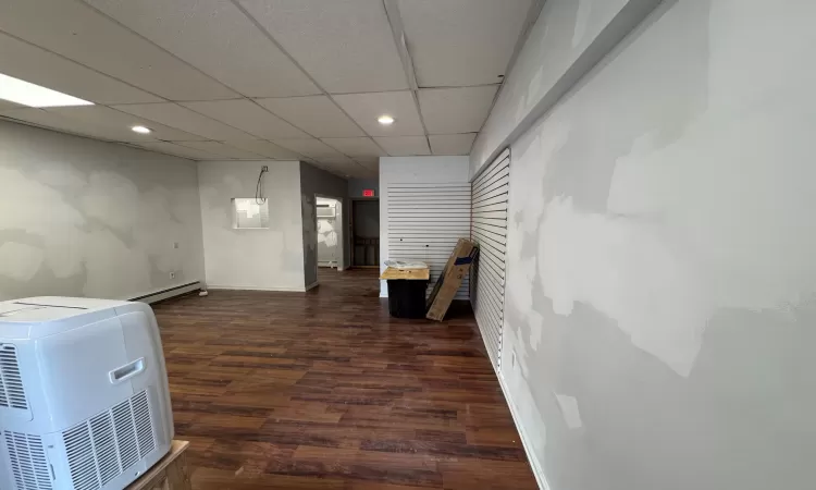 Hall with a drop ceiling, dark hardwood / wood-style floors, and baseboard heating