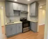 Kitchen featuring gas stove, gray cabinetry, and sink