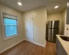 Kitchen featuring stainless steel fridge, light wood-type flooring, light stone counters, sink, and gray cabinets