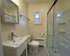 Bathroom with vanity, toilet, a shower with shower door, and radiator