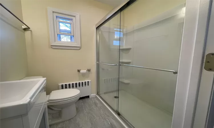 Bathroom featuring radiator, an enclosed shower, and toilet