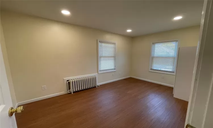 Spare room with radiator heating unit and dark hardwood / wood-style floors