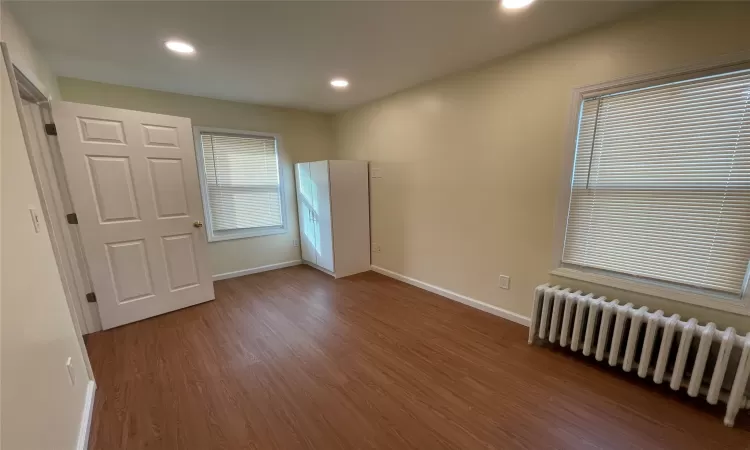 Spare room with radiator heating unit and hardwood / wood-style flooring