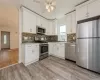 Kitchen with white cabinets, stainless steel appliances, light hardwood / wood-style floors, and sink