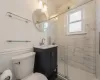 Bathroom with plenty of natural light, vanity, a shower with shower door, and toilet