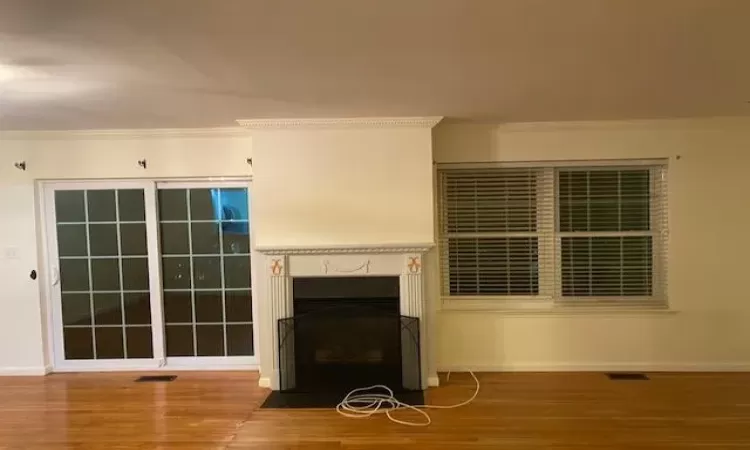 Unfurnished living room featuring hardwood / wood-style floors and ornamental molding