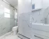 Bathroom featuring a baseboard radiator, an enclosed shower, toilet, vanity, and tile walls