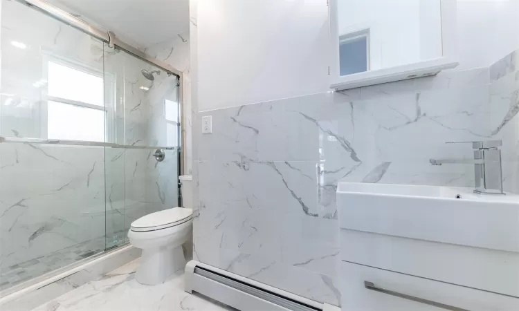 Bathroom featuring a baseboard radiator, an enclosed shower, toilet, vanity, and tile walls