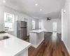 Kitchen with ceiling fan, dark hardwood / wood-style floors, a kitchen island, white cabinetry, and stainless steel refrigerator